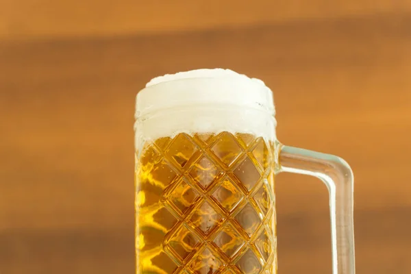 Craft cold light beer in a glass. Warm wooden background. Beer concept