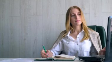 Kız öğrenci bir deftere monitörden bir dil dersi yazar. Çevrimiçi öğretmen kavramına sahip uzaklık dili kursu. Çevrimiçi eğitim kavramı