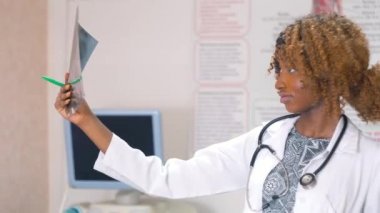 Kadın Afro-Amerikalı doktor klinikteki akciğerlerin röntgenini inceliyor. Tıp, sağlık ve insan kavramı