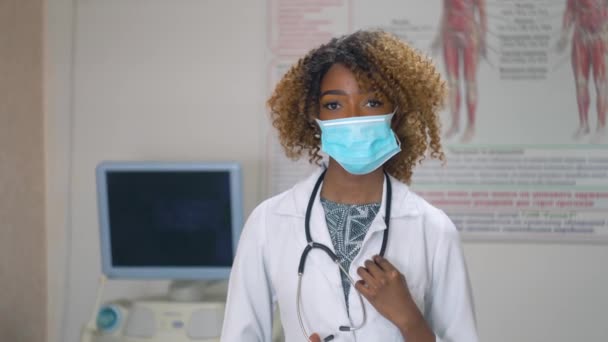 Profesyonel Afro-Amerikan kadın doktor portresi. Tıbbi maske takıyor. Arka planda ultrason cihazları olan hastane. Virüsü durdur — Stok video