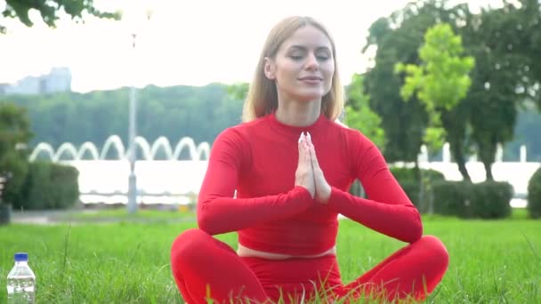 Mulher em vermelho pratica ioga no parque. Conceito de estilo de vida saudável — Vídeo de Stock