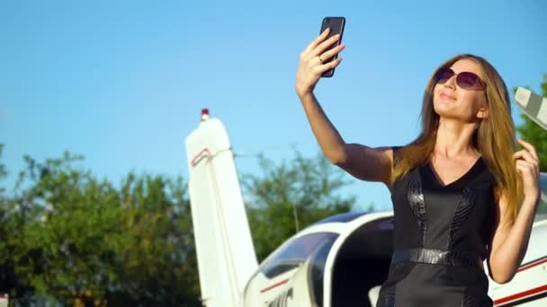 Kvinna som tar en selfie med smartphone framför parkerade små flygplan — Stockvideo