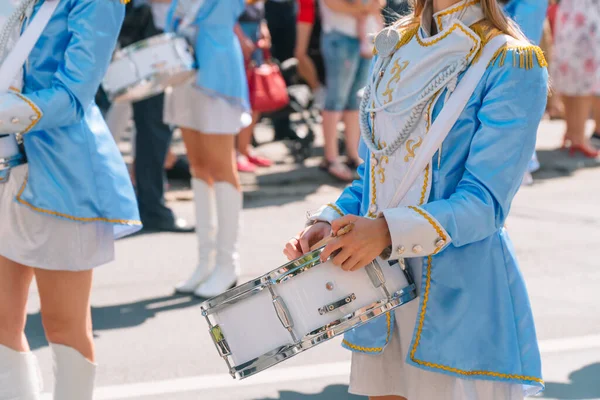 Actuación callejera de marcha festiva de bateristas niñas en trajes azules en la calle de la ciudad. Primer plano de las manos femeninas bateristas están golpeando en el tambor de sus palos —  Fotos de Stock