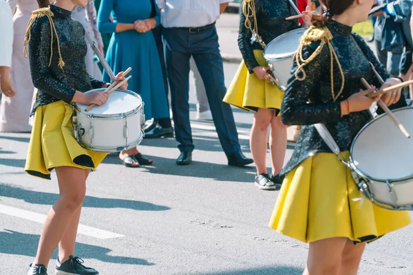 Desempenho de rua de marcha festiva de meninas de bateristas em trajes pretos amarelos na rua de cidade. Conceito de música urbana — Fotografia de Stock