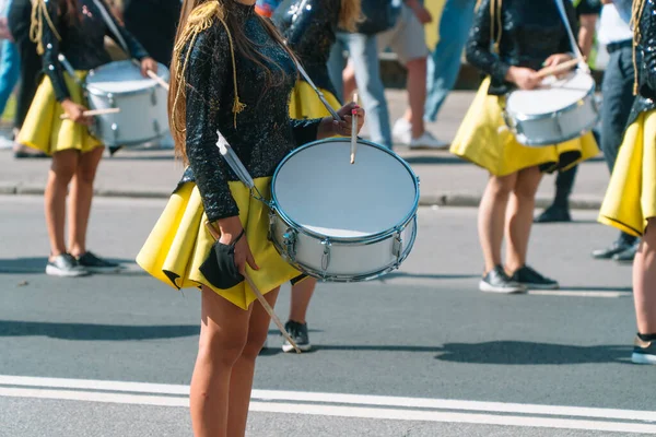 Desempenho de rua de marcha festiva de meninas de bateristas em trajes pretos amarelos na rua de cidade. Conceito de música urbana — Fotografia de Stock