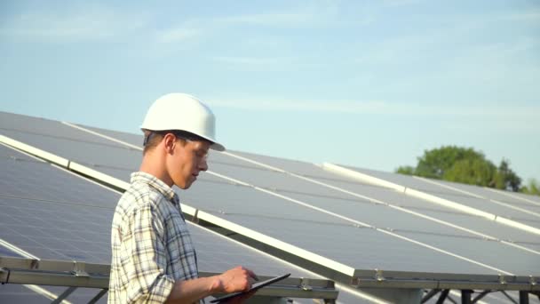 Técnico de paneles solares que trabaja con paneles solares. Ingeniero con una tableta comprueba la productividad de los paneles solares. Concepto de energía alternativa — Vídeo de stock