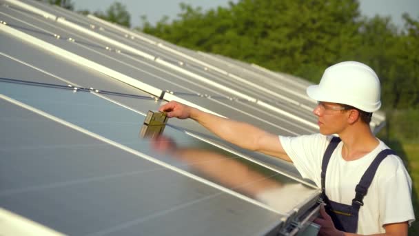 Mladý motor instaluje nové slunné baterie. Pracovník v uniformě a klobouku instalující fotovoltaické panely na solární farmě. Koncept zelené energie — Stock video