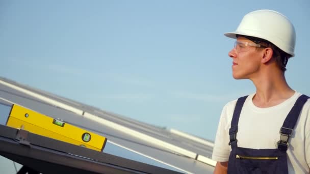 Unga enginneer installerar nya soliga batterier. Arbetare i en uniform och hatt som monterar solcellspaneler på en solgård. Framtiden är i dag. Begreppet grön energi — Stockvideo