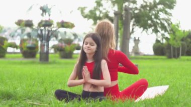 Güzel ve sağlıklı kadın ve küçük kız nilüfer çiçeği ya da sukhasna pozunda oturur, meditasyon yapar ya da yoga ve pranayama yapar. Doğada beden ve zihin gevşesin.