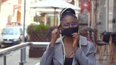 Afrikalı Amerikalı bir kız tıbbi bir maske çıkarıyor. Sosyal güvenlik önlemleriyle işe geri döndüm. Karantina sona erdi. Virüsü durdur