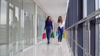 Alışveriş çantalı iki kız alışveriş merkezinde yürüyor. Alışveriş konsepti. Salgının sonu