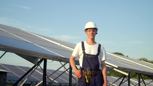 Techniker für Sonnenkollektoren arbeitet mit Sonnenkollektoren. Glücklicher junger Mann, der Unterricht auf dem Hintergrund von Sonnenkollektoren zeigt. Die Zukunft liegt heute — Stockvideo