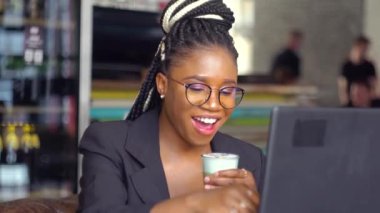 Afro-Amerikalı genç kız, kafede sohbet ederek akrabalarıyla sohbet ediyor ve kahve içiyor.