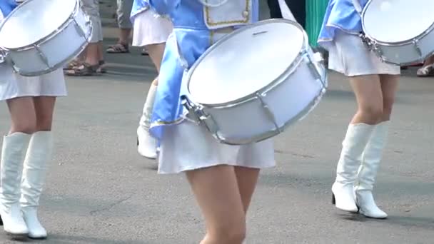 Вуличне виконання святкового маршу дівчаток барабанщиків у блакитних костюмах на міській вулиці. Крупним планом жіночі руки барабанщики стукають в барабан своїх паличок — стокове відео