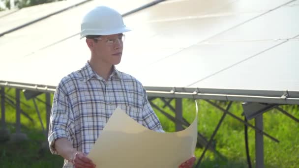 Ingenjör i vit hjälm är vid solkraftverket. Solcellspanel — Stockvideo