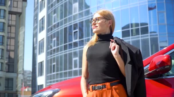 Attraktiv snygg kvinna med långt hår nära lyx bil på en byggnad bakgrund — Stockvideo