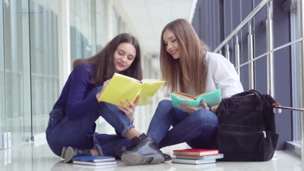 Két diáklány egy könyvvel az iskolában. Kezdődik a tanév. Új, modern, teljesen működőképes oktatási létesítmény. Az online oktatás fogalma — Stock videók