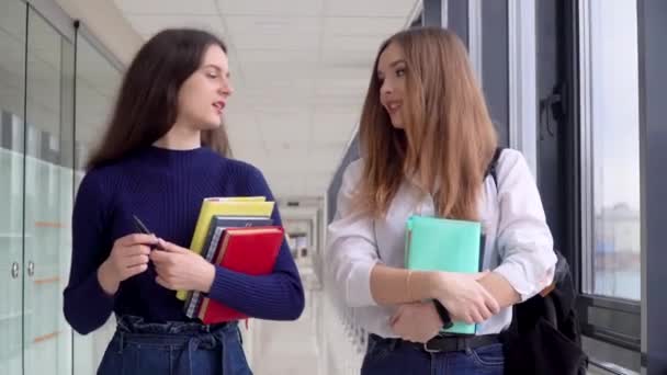 Két diáklány egy könyvvel az egyetemen. Kezdődik a tanév. Új, modern, teljesen működőképes oktatási létesítmény. Az online oktatás fogalma — Stock videók