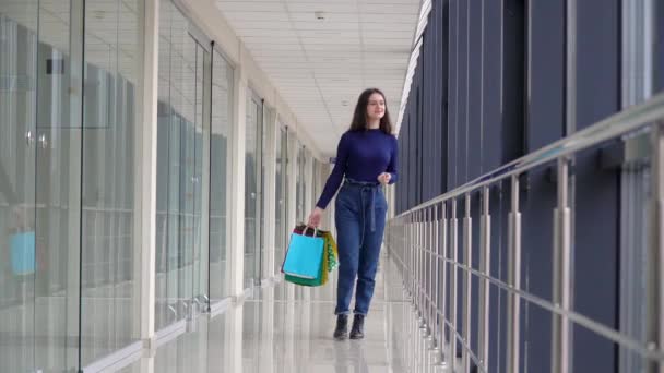 Gelukkig meisje met boodschappentassen lopend in een winkelcentrum. Grote verkoop in het winkelcentrum. Winkelconcept — Stockvideo