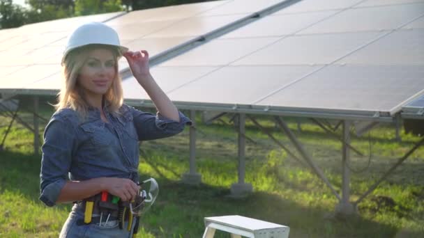 Жінка-інженер у білому шоломі знаходиться на сонячній електростанції. Концепція зеленої енергії — стокове відео