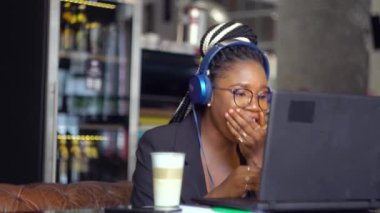 Çalışmak için dizüstü bilgisayar kullanan genç siyah bir kadın, online dersler, atölyeler ve yüksek lisans dersleri izliyor. Video sohbet iş görüşmesi ya da uzaktaki dil kursu konsepti