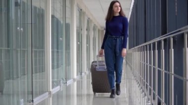 Havaalanında bavullu bir yolcu yürüyor. Bavullu genç bayan havaalanına gidiyor. Karantina sonrası seyahat