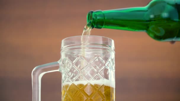 Pouring beer into a glass from a glass bottle. Close-up of foamy beer — Stock Video