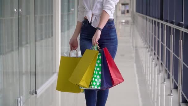 Fiatal lány színes bevásárlótáskákkal a bevásárlóközpontban. Karantén utáni vásárlás — Stock videók
