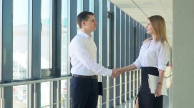 Modern bir ofiste iş adamı ve kadın tokalaşıyor.