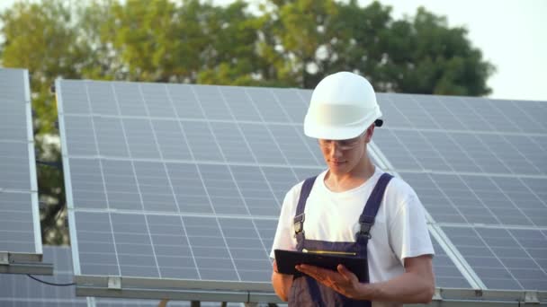 Techniker für Sonnenkollektoren arbeitet mit Sonnenkollektoren. Ingenieur in Uniform mit Tablet überprüft die Produktivität der Solarmodule. Die Zukunft liegt heute — Stockvideo