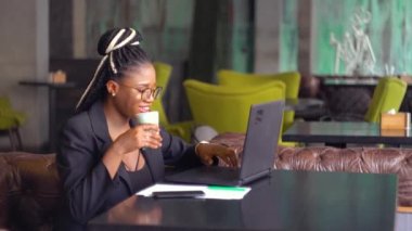 Gülümseyen siyah kız arkadaşlarıyla sohbet ediyor ve kahve içiyor.