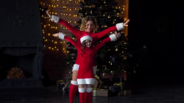 クリスマスの衣装を着た母と娘はクリスマスツリーの近くでクリスマスを祝う — ストック動画