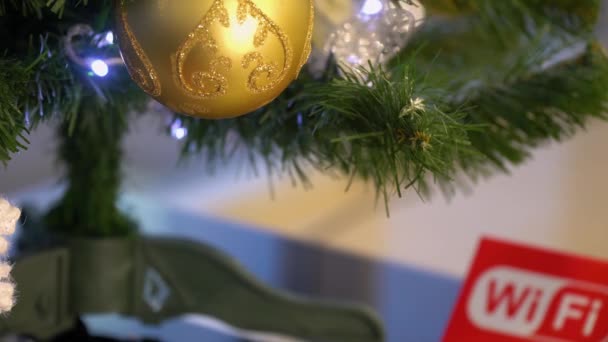 Glänzend goldene Christbaumkugel auf dem künstlichen Baum im Büro mit Wi-Fi-Wort. Goldfarben. Weihnachtsschmuck. Kostenlose WLAN-Zone — Stockvideo