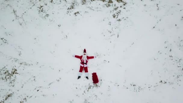 Санта Клаус лежит на снежном пляже. Вид сверху. Камера движется к вершине. Санта в Арктике — стоковое видео