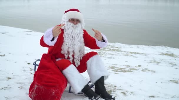 Bad Santa Claus shows the fuck you middle finger on the snowy beach — Stock Video