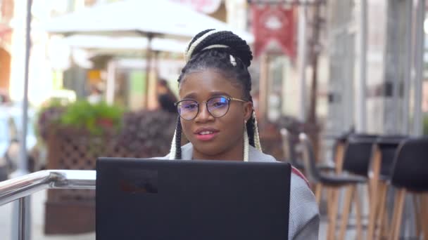 Den afroamerikanska kvinnan på kaféet jobbar på sin laptop. Tillbaka till arbetet med sociala avståndsåtgärder — Stockvideo