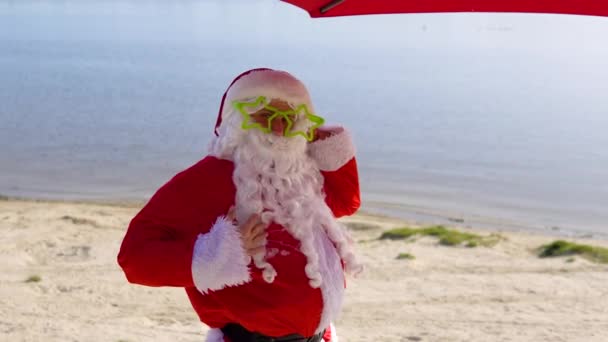 Papai Noel em óculos engraçados na praia do oceano — Vídeo de Stock