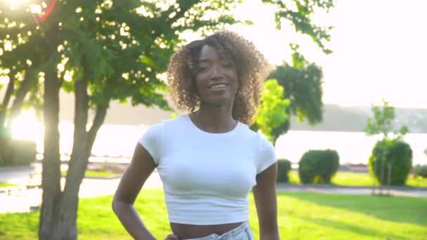 美丽的年轻非洲裔美国女人漂亮的脸蛋看着镜头独自在公园里摆姿势 — 图库视频影像