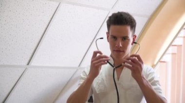 Profesyonel doktor steteskopla poz veriyor. Tıp bürosundaki kameraya bakıyor. Tıp, sağlık ve insan kavramı