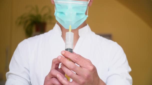 Junger Arzt in Schutzmaske bereitet Spritze für Injektion vor. Nahaufnahme einer jungen Praktikantin im Krankenhaus — Stockvideo