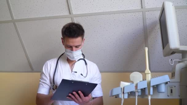 Mladý doktor se zápisníkem v moderní nemocnici. Doktor vyšetřuje anamnézu pacientů. Pojem medicína, zdravotní péče a lidé — Stock video