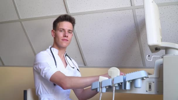 Un médico joven trabajando en un dispositivo de ultrasonido. Diagnósticos covid 19 — Vídeos de Stock