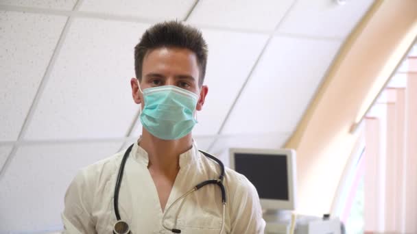 Retrato de médico profissional com estetoscópio em máscara protetora. Hospital com dispositivos de ultra-som em segundo plano — Vídeo de Stock