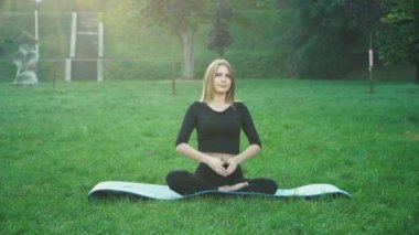 Genç bir kadın parkta yoga yapıyor. Sağlıklı yaşam tarzı kavramı