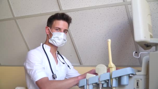 超音波装置の保護マスクの若い医師。診断｜covid 19 — ストック動画