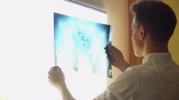 Le jeune médecin examine la radiographie de la colonne vertébrale à la clinique. Diagnostic de lésion médullaire. Concept de médecine, de soins de santé et de personnes — Video