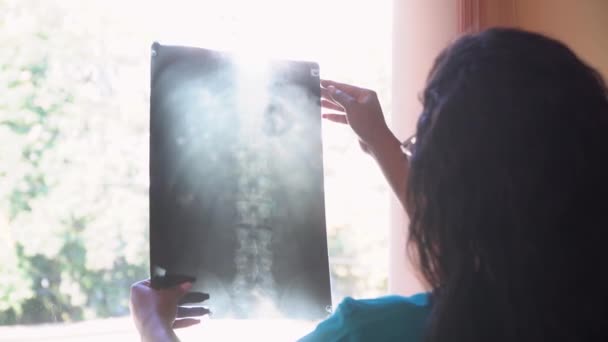Médica afro-americana examina raio-X da coluna vertebral na clínica. Diagnóstico de lesões na coluna. Conceito de medicina, cuidados de saúde e pessoas — Vídeo de Stock
