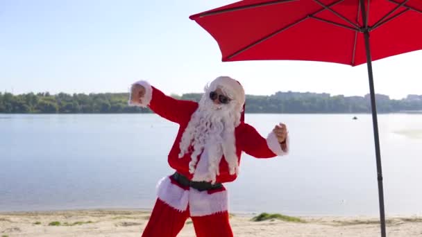 Święty Mikołaj bawi się i tańczy w stylu klubowym na plaży. Święta Bożego Narodzenia — Wideo stockowe