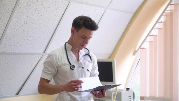 Junger Arzt untersucht Krankengeschichte des Patienten — Stockvideo