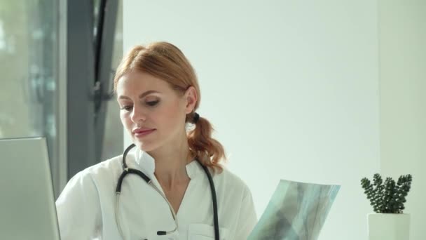 Médica do sexo feminino examina a varredura de raios X e digite o resultado no laptop — Vídeo de Stock